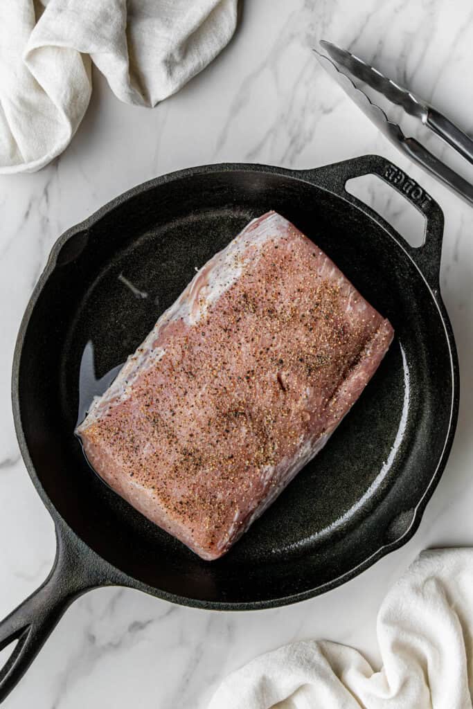 Flat lay shot of the seasoned meat cut placed on a heated skillet with oil.