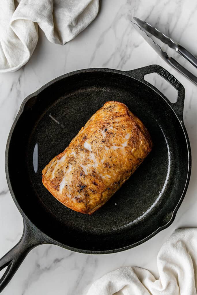 Flat lay shot of the seared meat, looking considerably smaller, in the cast iron skillet.
