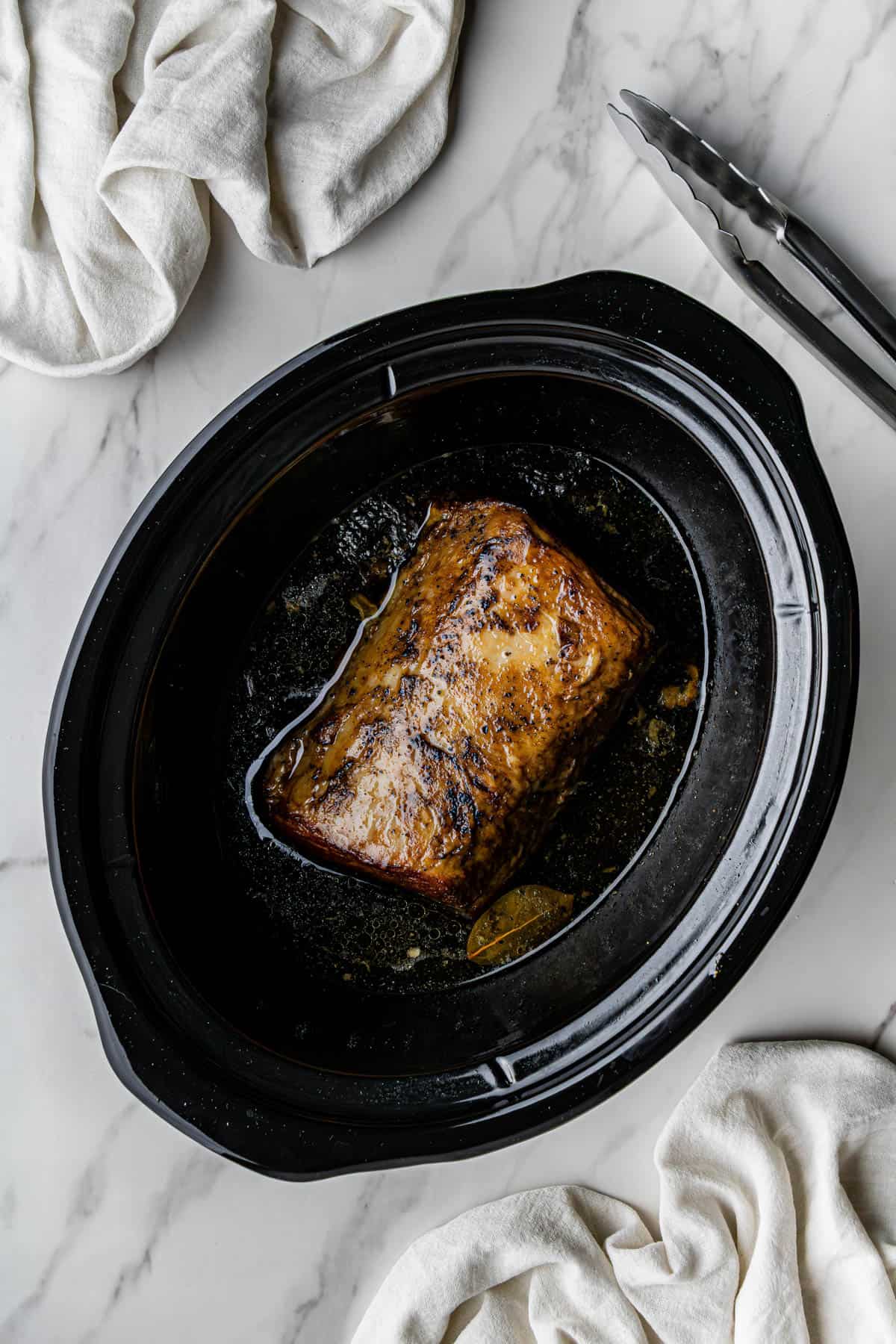 Flat lay shot of the cooked meat in a slow cooker.