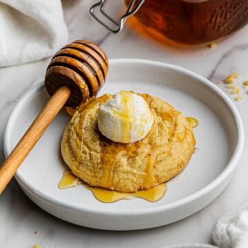A single Crumbl Cornbread Cookies Copycat recipe drizzled with honey, placed on a white ceramic plate.