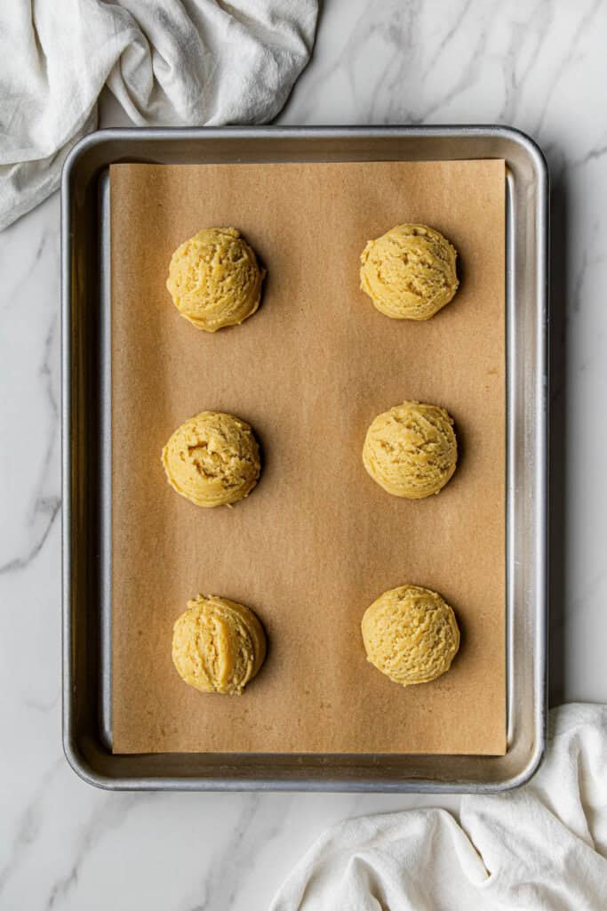 Flat lay shot of a sheet tray with dough balls in it, about to be baked.