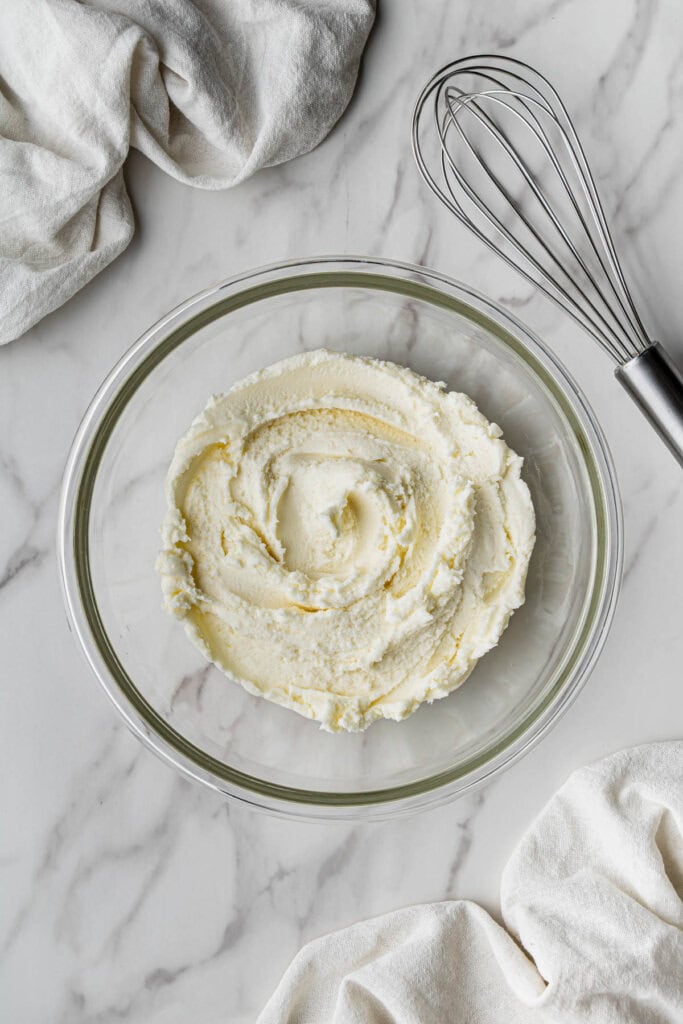 A flat lay shot of a glass bowl with the finished buttercream frosting.