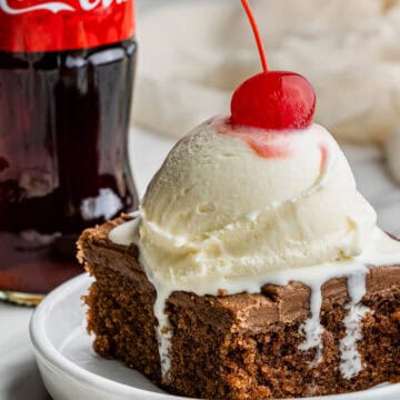 A slice of the cracker barrel Coca-Cola Cake recipe with a scoop of vanilla ice cream with a cherry on top.