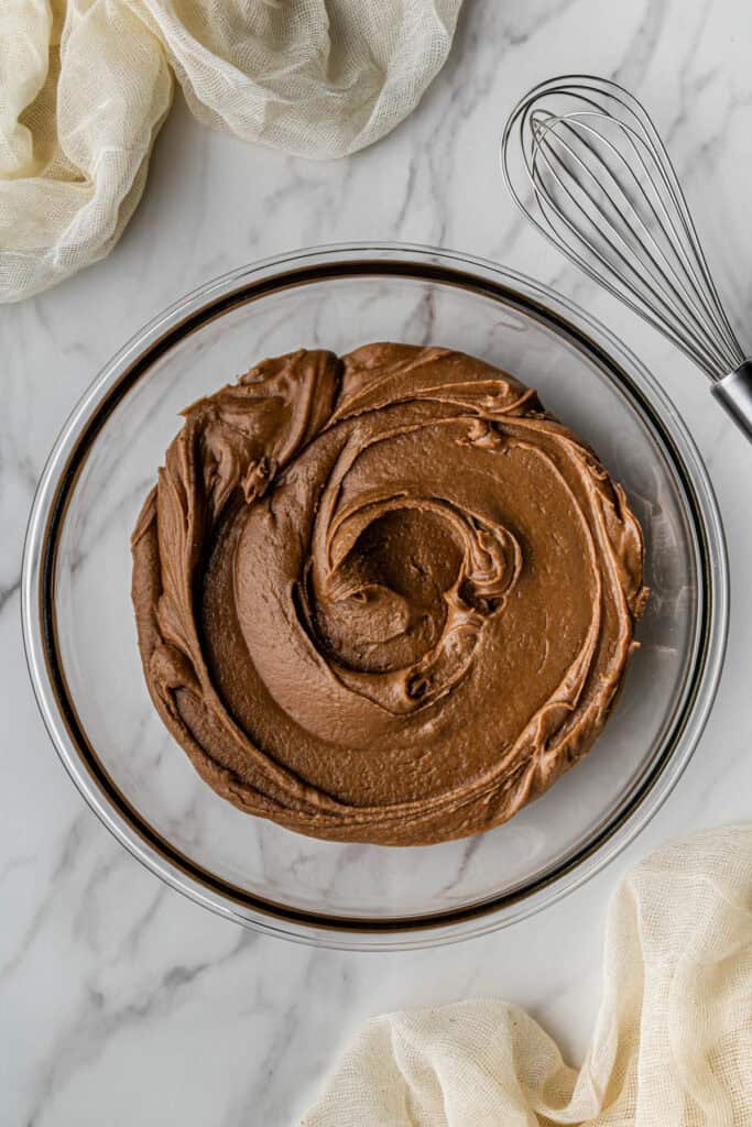 A glass bowl with the fudgy chocolate frosting in it.