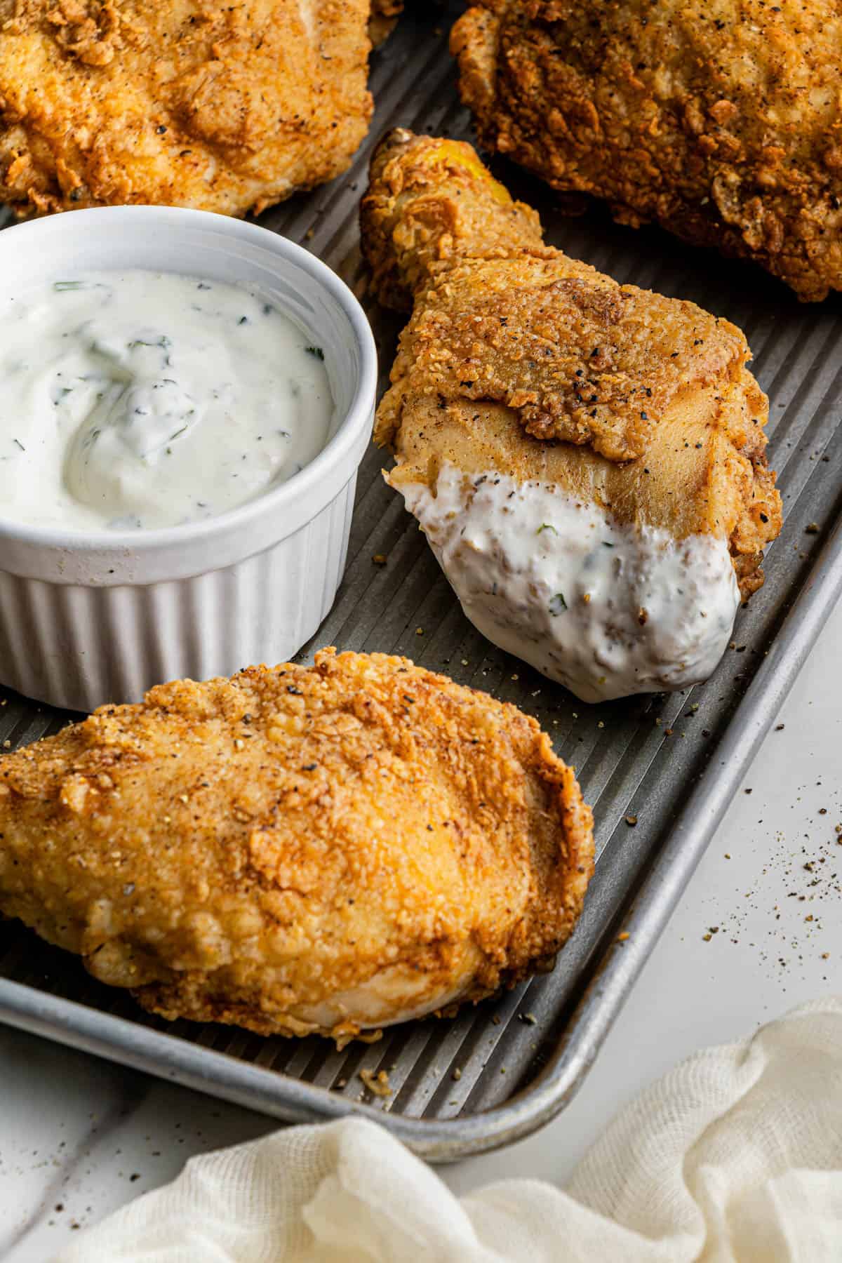 A batch of Cracker Barrel Southern Fried Chicken on a sheet tray with a ramekin filled with cool ranch dip.