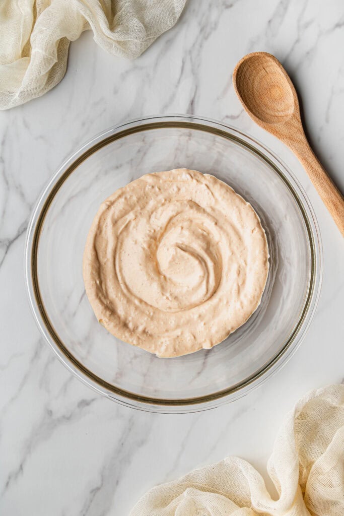 Flat lay shot of a glass bowl with the mixed ingredients placed on a marble surface.