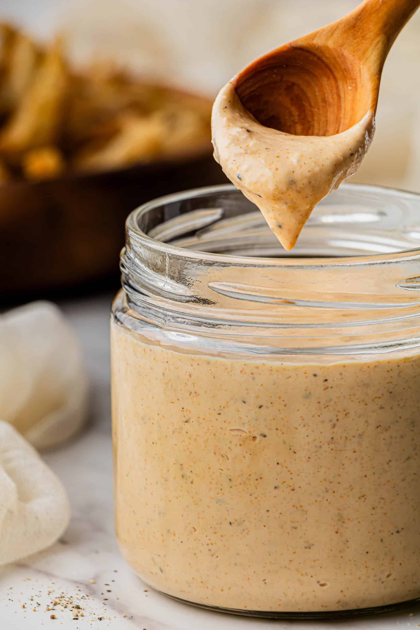 A wooden spoon with the outback Bloomin' Onion sauce copycat recipe in its tip being pulled up from a jar.
