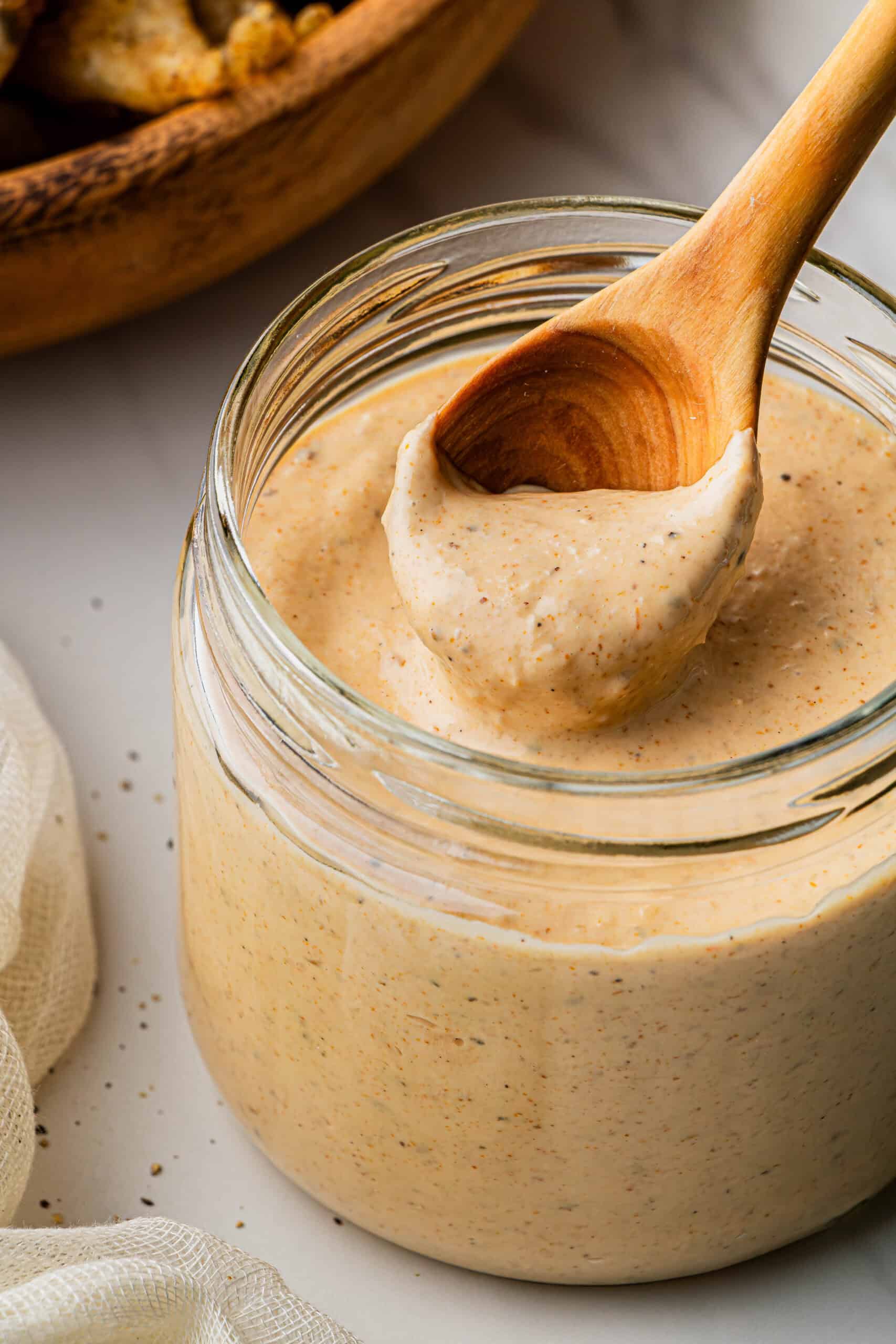 A spoonful of the outback Bloomin' Onion Sauce copycat recipe being taken out from a glass jar.