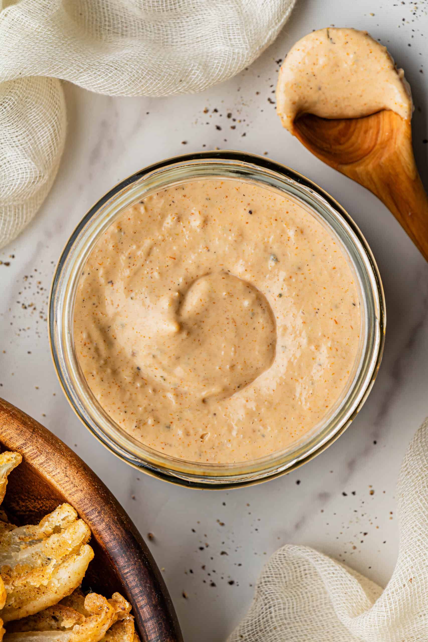 A glass bowl with dip in it. The glass bowl is placed on a marble surface.