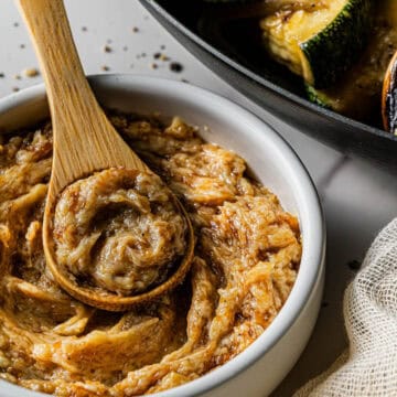 A wooden spoon with a dollop of Benihana Copycat Garlic Butter, resting on a small white dish with more garlic butter.