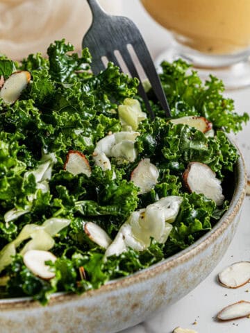 A serving of the best Chick-Fil-A Copycat Kale Crunch Salad in a bowl with a fork taking a bite out of it.