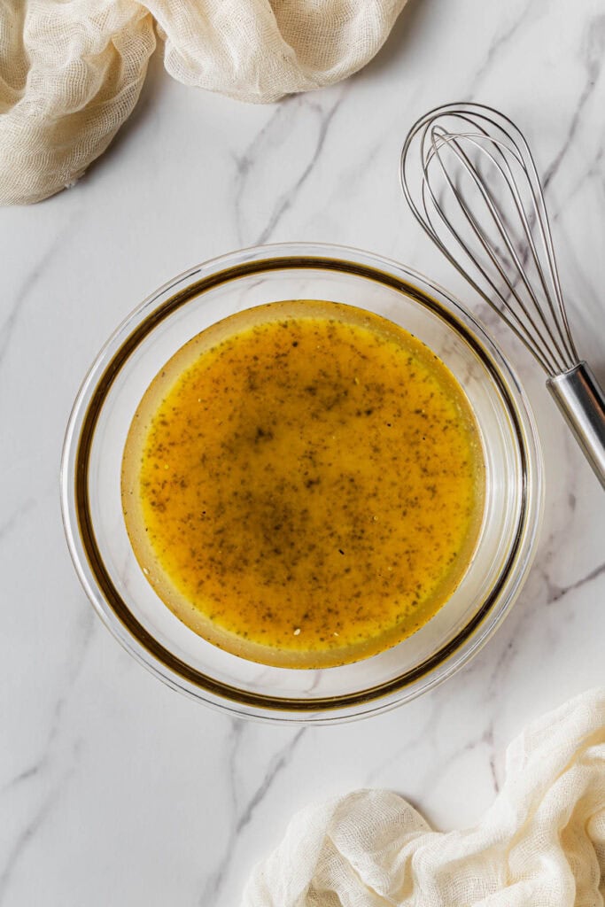 A glass bowl with dressing in it.