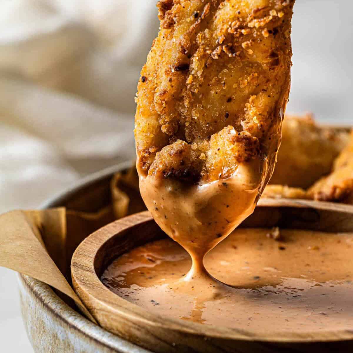 Crispy chicken tender dipped into creamy spicy dipping sauce