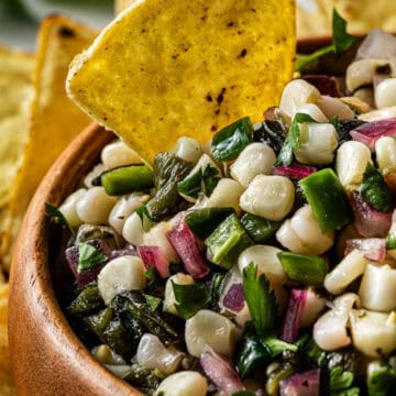 Copycat Chipotle corn salsa in a wooden bowl with a tortilla chip