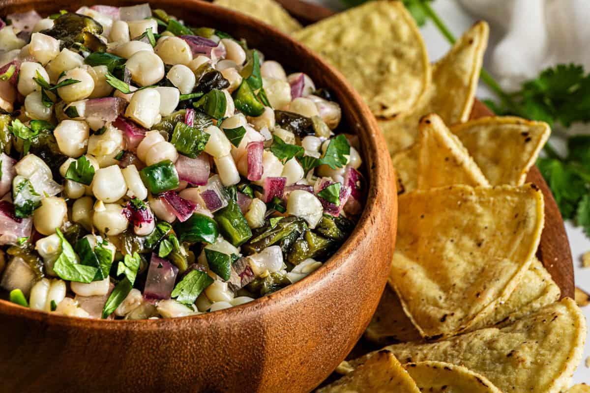 Homemade Chipotle corn salsa in a wooden bowl with tortilla chips on the side