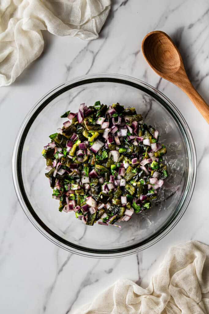 Red onion, roasted poblano, jalapeño, and cilantro mixed in a glass bowl