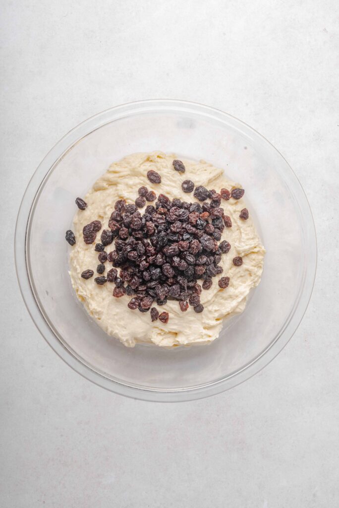 raisins on top of cookie dough in clear bowl