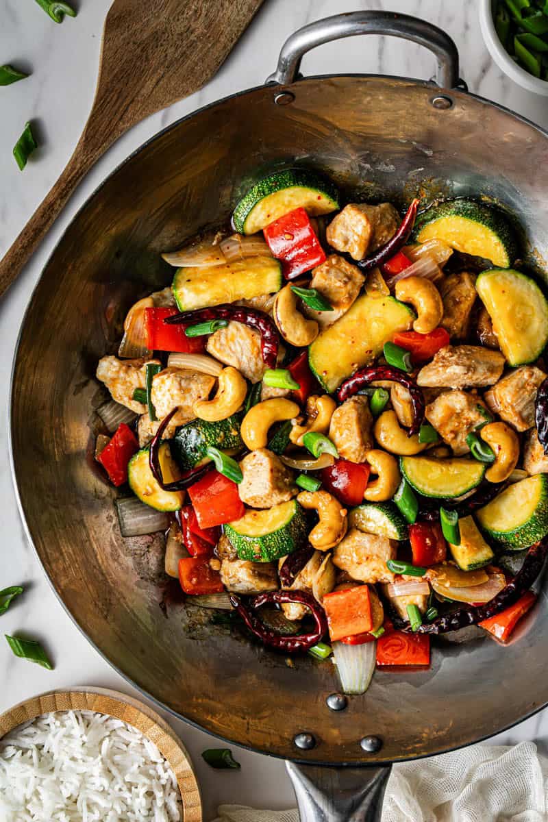 Panda Express kung pao chicken copycat in a carbon steel wok with a side of white rice and scallions