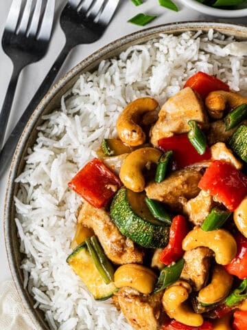 Bowl of Panda Express kung pao chicken copycat with white rice, cashews, zucchini, and red bell pepper