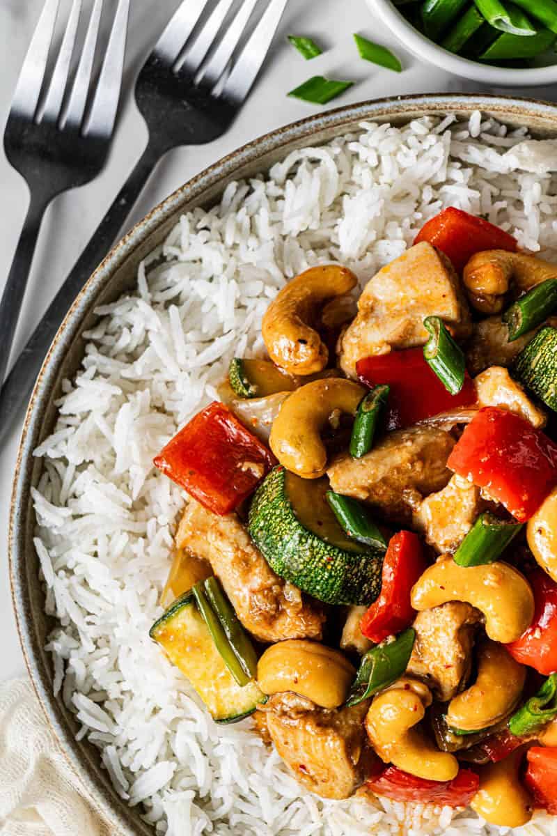 Bowl of Panda Express kung pao chicken copycat with white rice, cashews, zucchini, and red bell pepper