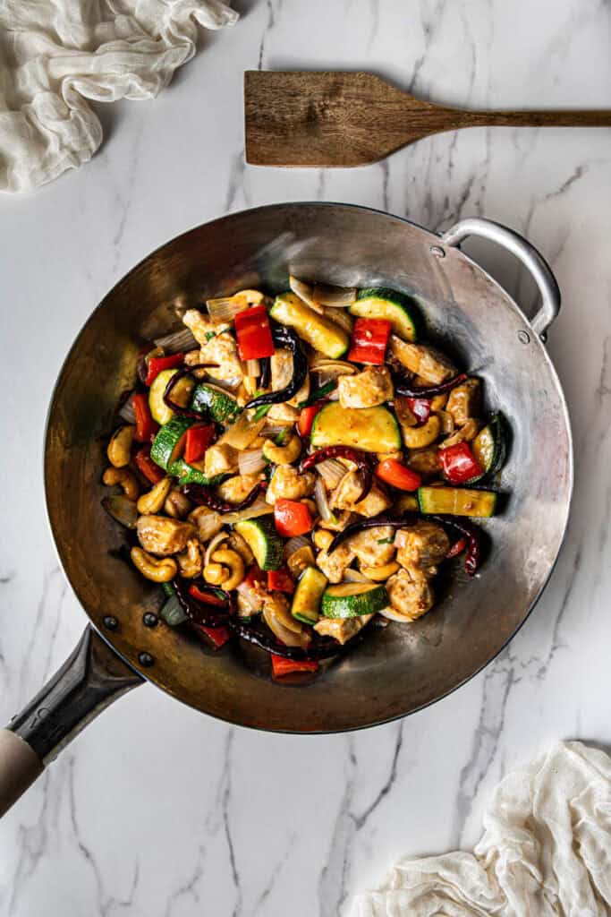 Finished Panda Express kung pao chicken copycat with chicken, zucchini, red bell pepper, cashews, and dried chilies in a wok