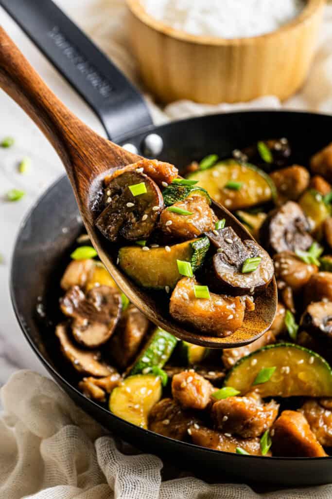 Spoon lifting mushroom chicken with zucchini and mushrooms