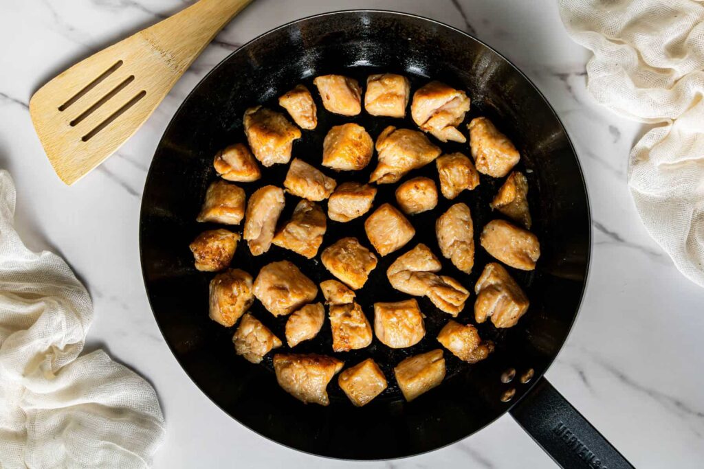 Chicken pieces searing in skillet for mushroom chicken