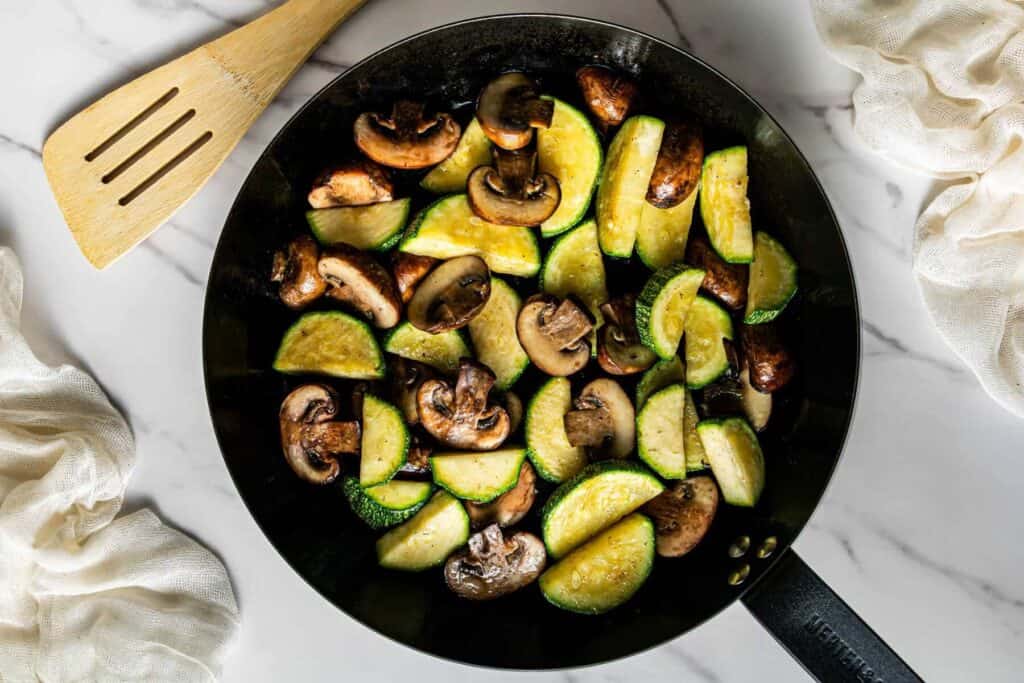 Mushrooms and zucchini sautéing in skillet