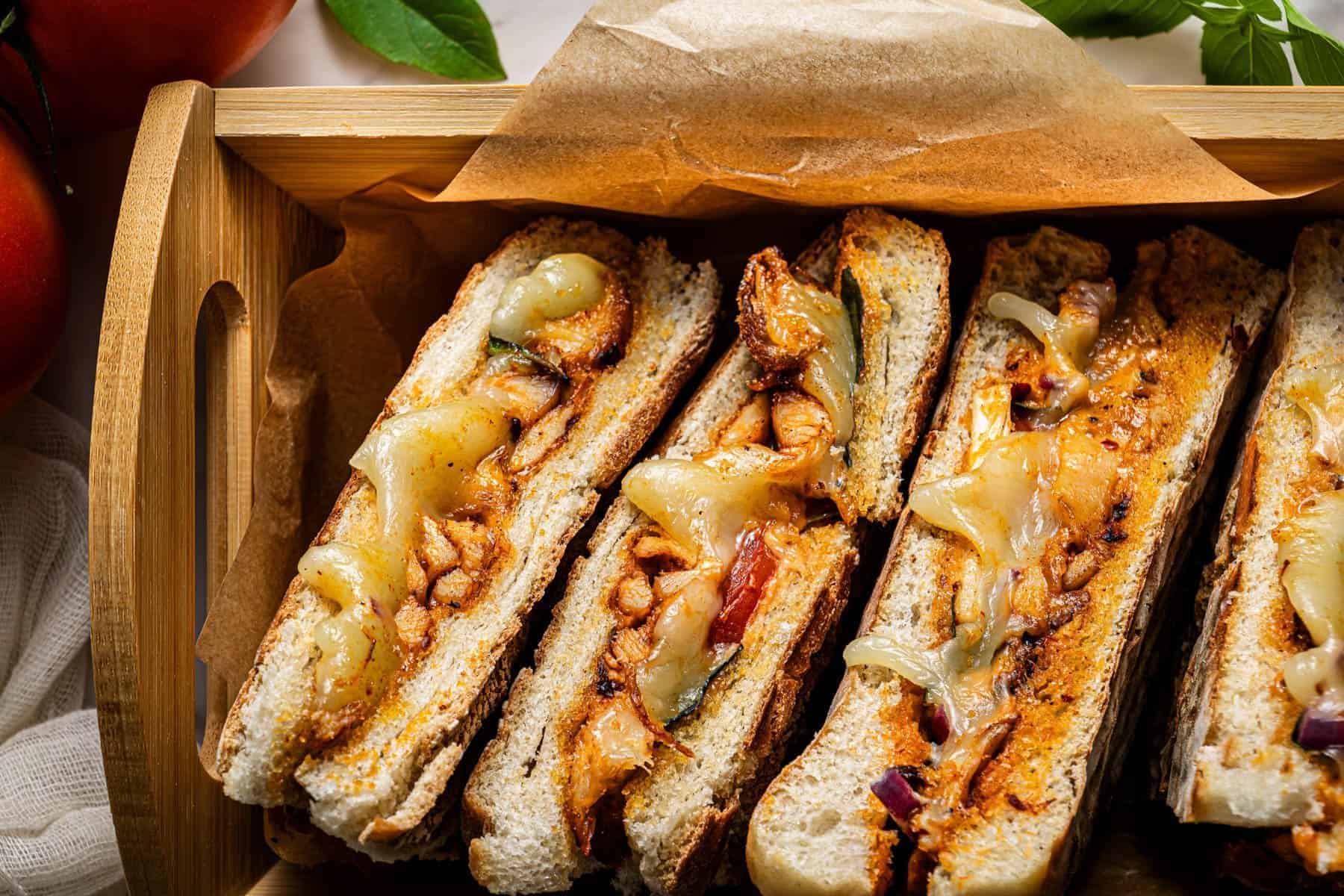 Grilled chicken panini sandwiches served in a tray lined with parchment paper