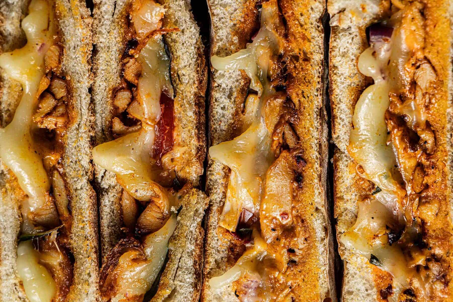 Several grilled chicken panini slices arranged on a tray for serving