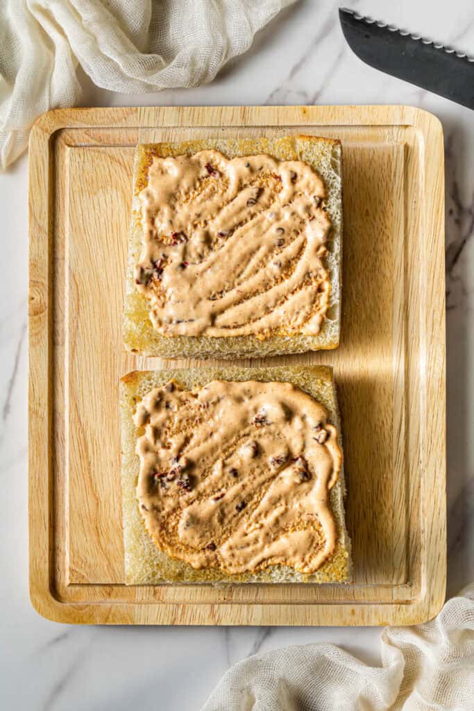 Chipotle mayo spread onto toasted focaccia bread slices before assembling sandwich