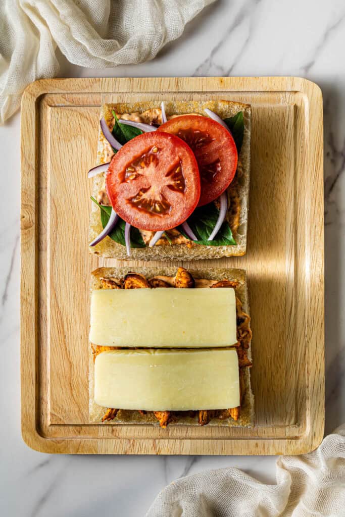 Chicken, mozzarella cheese, tomato slices, onion, and basil layered on focaccia bread before grilling