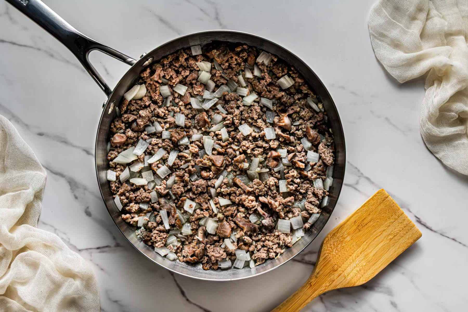 Ground beef and minced chicken gizzards browning in skillet for Popeye’s Cajun Rice