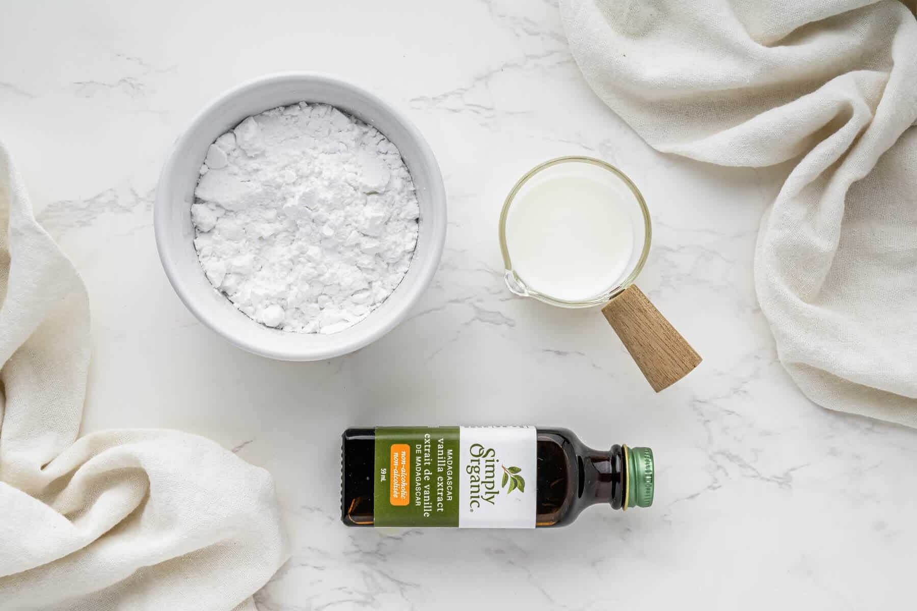 overhead view of icing ingredients in cups and bottle